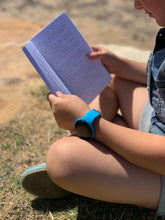 Load image into Gallery viewer, Person sitting outdoors reading a book with a blue Pjama Vibrating on