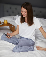 Load image into Gallery viewer, Teenager sitting on a bed holding a phone, wearing Pjama grey long pants