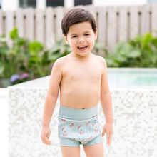 Load image into Gallery viewer, Child wearing light blue swim shorts with a otter pattern, standing by a pool.