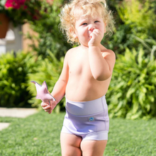 Load image into Gallery viewer, Child wearing a light lilac swiming shorts outdoors with greenery in the background
