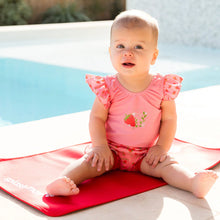 Load image into Gallery viewer, Baby in a pink swimsuit sitting on a red and white mat by a pool
