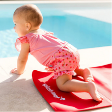 Load image into Gallery viewer, Baby in a pink swimsuit sitting on a red 'Splash Mat' by a pool.
