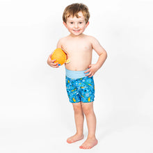 Load image into Gallery viewer, Young boy wearing blue swim shorts with a pattern, holding an orange ball, on a white background
